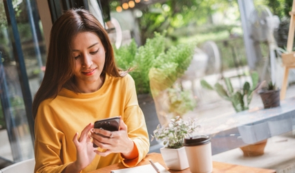 Woman smiling at her phone while browsing the news feed