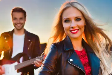 Man plying guitar for woman at outdoors date