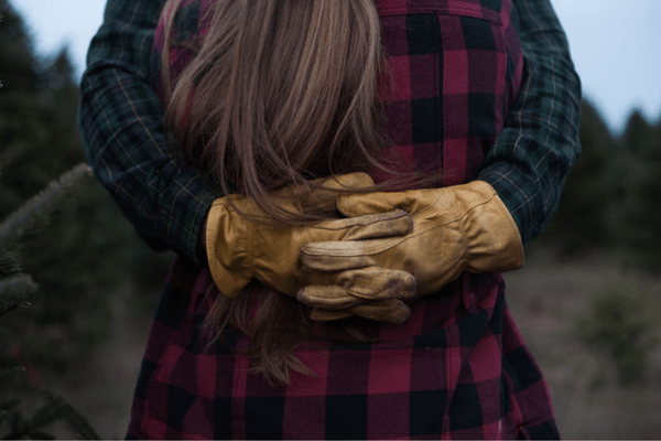 Couple hugging in countryside, man wearing work gloves
